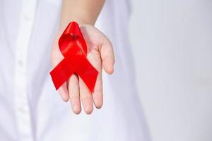 Die Hände des Mädchens halten ein rotes Brustkrebs-Bewusstseinsband und ein Aids-Bewusstseinsband foto