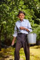 alter Bauer, der in einem Obstgarten düngt