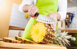 Frauenhände schneiden Ananas foto