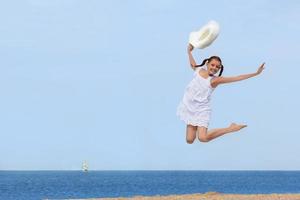 fröhliches Mädchen, das über das Wasser am Strand springt foto