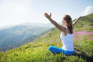 junge Frau meditieren auf dem Gipfel des Berges foto