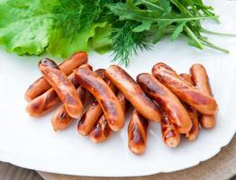 gegrillte Würstchen auf dem Grill und ein Salat aus frischem Gemüse foto