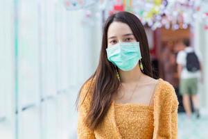 asiatische frau mit langen haaren trägt orangefarbene strickwaren und medizinische gesichtsmaske im gesundheitswesen, neues normales konzept. foto