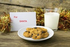 Kekse und ein Glas Milch mit einer weißen Note für Santa foto
