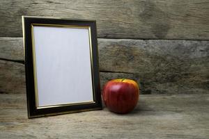 Holzfotorahmen und roter Apfel auf Holztisch foto