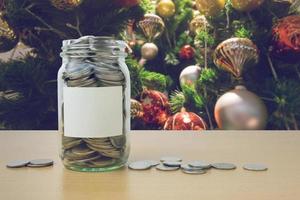 geld in der glasflasche mit geschmücktem weihnachtsbaum hintergrundunschärfe foto