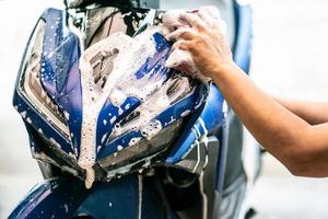 Biker Scooter waschen. motorrad mit schwamm oder weichem tuch in der garage reinigen, reparatur- und wartungsmotorradkonzept. foto