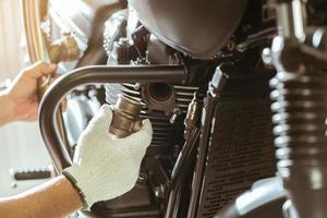 mechaniker installieren motorrad-auspuffanlage in der garage, konzept der wartung und reparatur von motorrad. selektiver Fokus auf Zylinderblock foto