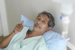 porträt eines älteren patienten, der im krankenhaus, im gesundheitswesen und im medizinischen konzept auf dem bett liegt foto