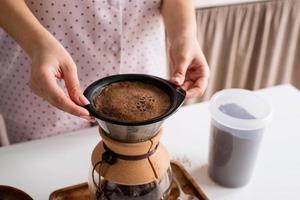 junge frau im schönen pyjama, die zu hause küche kaffee kocht foto