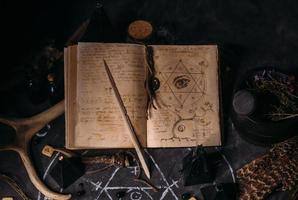 offenes altes buch mit zaubersprüchen, runen, schwarzen kerzen auf hexentisch. okkultes, esoterisches, Wahrsagerei- und Wicca-Konzept. foto