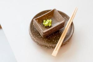 Wasabi in brauner Tasse und Essstäbchen foto
