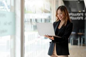 junge asiatische Geschäftsfrau, die online auf einem Laptop arbeitet foto