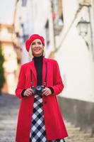 lächelnde weibliche touristin mit fotokamera, die auf treppen auf der stadtstraße steht foto