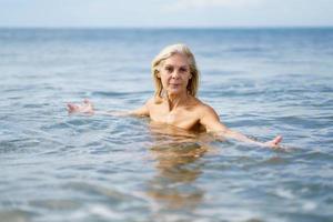 Reife Frau in guter Verfassung, die im Meer badet. foto