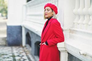 Modische Frau in der Nähe von weißem Zaun im städtischen Hintergrund foto