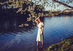 schönes Mädchen im Vintage-Kleid, das im Wasser steht foto