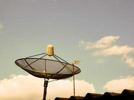 TV-Satellitenschüssel auf dem Dach des Hauses am Abend foto