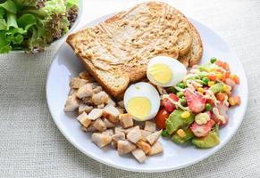 Sauberes Essen im modernen Stil, Erdnussbutter mit Brot, gekochtes Ei, gegrilltes Hähnchen und Avocado, Erdbeere, Gemüsesalat foto