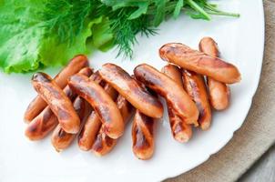 gegrillte Würstchen auf dem Grill und ein Salat aus frischem Gemüse foto