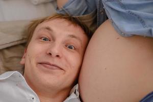 der zukünftige Vater lauscht, wie sein Kind im Bauch seiner schwangeren Frau schlägt. foto