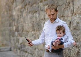 Ein junger Vater telefoniert mit einem Handy und hält seine kleine Tochter im Arm. Platz kopieren foto