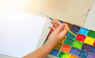 Kinderhandbürste und Normalpapier mit quadratischer Farbpalette für Kunstwerke, Draufsicht foto