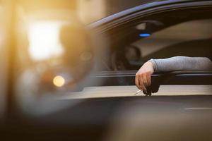 hand halten cigarratte mit den fingern außerhalb des autos auf verkehrsfahrt foto