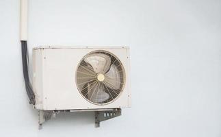 Kompressor der Klimaanlage zeigt Flügel des Lüfters innen an der Wand außerhalb des Gebäudes mit kühlerer Flüssigkeitsleitung foto