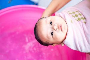 asiatische mutter dusche baby zum reinigen von schmutz geben kind im bad behälter für sauberkeit lebensstil familie zwischen mutter und kind verwendet für babydusche cremeprodukte shampoos lotionen und babypflegeprodukt foto