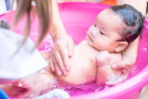 asiatische mutter dusche baby zum reinigen von schmutz geben kind im bad behälter für sauberkeit lebensstil familie zwischen mutter und kind verwendet für babydusche cremeprodukte shampoos lotionen und babypflegeprodukt foto