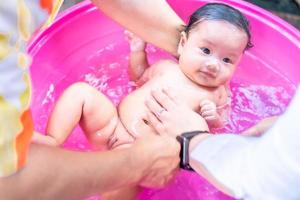 asiatische mutter dusche baby zum reinigen von schmutz geben kind im bad behälter für sauberkeit lebensstil familie zwischen mutter und kind verwendet für babydusche cremeprodukte shampoos lotionen und babypflegeprodukt foto