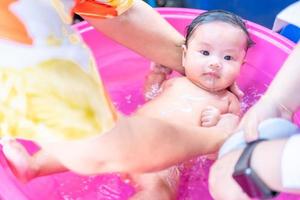 asiatische mutter dusche baby zum reinigen von schmutz geben kind im bad behälter für sauberkeit lebensstil familie zwischen mutter und kind verwendet für babydusche cremeprodukte shampoos lotionen und babypflegeprodukt foto