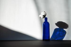 blaue Glasflasche mit einer Baumwollblume foto