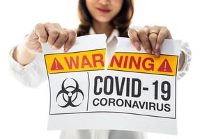 frau, die papier mit covid-19-coronavirus-warnwörtern hält und zerreißt. die idee oder das konzept für das ende, glück, frei und wohlbefinden nach abschluss und genesen von coronarivus foto