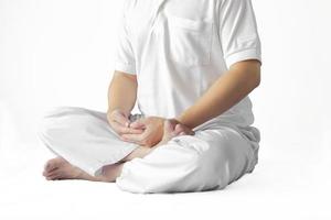 Ein Mann in einem weißen Gewand, der vor einem weißen Hintergrund mit einem Beschneidungspfad meditiert. foto