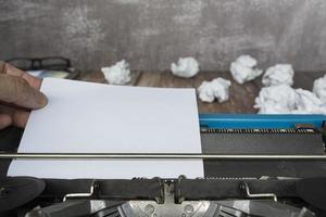 Hand, die ein Stück weißes Papier von einer alten klassischen Schreibmaschine zieht. Platz kopieren. foto