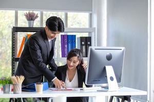 männliche und weibliche kollegen des geschäftsteams, die sich bei der arbeit unterhalten, tauschen ideen mit laptop aus, glückliche junge kollegen arbeiten zusammen am computer foto