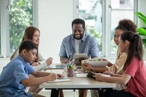 glücklicher lehrer, der schüler im klassenzimmer unterrichtet. lehrer und schüler arbeiten gemeinsam am schreibtisch in der schule. foto