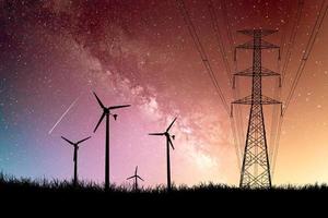 eine Silhouette einer Windmühle, die zur Stromerzeugung auf einem Feld vor einer wunderschönen Milchstraßenkulisse verwendet wird. foto