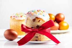 Osterkuchen Panettone mit süßem Zuckerguss und goldenen Eiern auf weißem Teller. foto