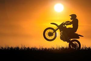 Silhouette eines Motocross-Motorrads, das das Vorderrad anhebt. Abenteuer- und Aktionskonzepte foto