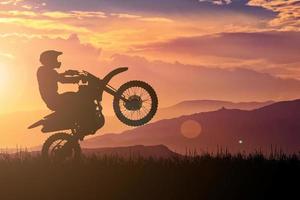 Silhouette eines Motocross-Motorrads, das das Vorderrad anhebt. Abenteuer- und Aktionskonzepte foto