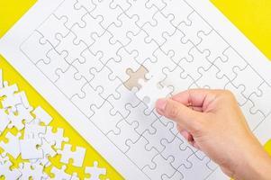Puzzle und Hände auf dem gelben Konzepthintergrund foto