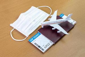 Reisen während der Covid-19-Pandemie. Flugzeugmodell mit Gesichtsmaske, Flugticket und Reisepass. bereit für den Urlaub. foto