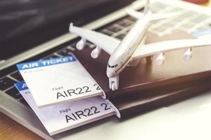 Flugtickets und Pässe in der Nähe von Laptop-Computer und Flugzeug auf dem Tisch. Online-Ticket-Buchungskonzept foto