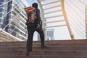 Geschäftsmann in einem Anzug mit Rucksack und Wanderstöcken in der Stadt foto