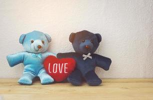 Schöner Teddybär und rote Herzform, die auf einem Holztisch sitzen foto