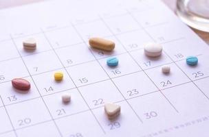 Haufen verschiedener Pillen auf einem Kalenderhintergrund. Konzept Gesundheitswesen foto