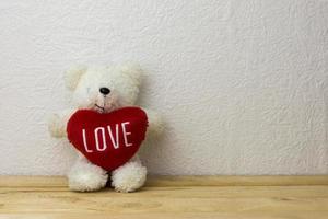 Schöner Teddybär und rote Herzform, die auf einem Holztisch sitzen